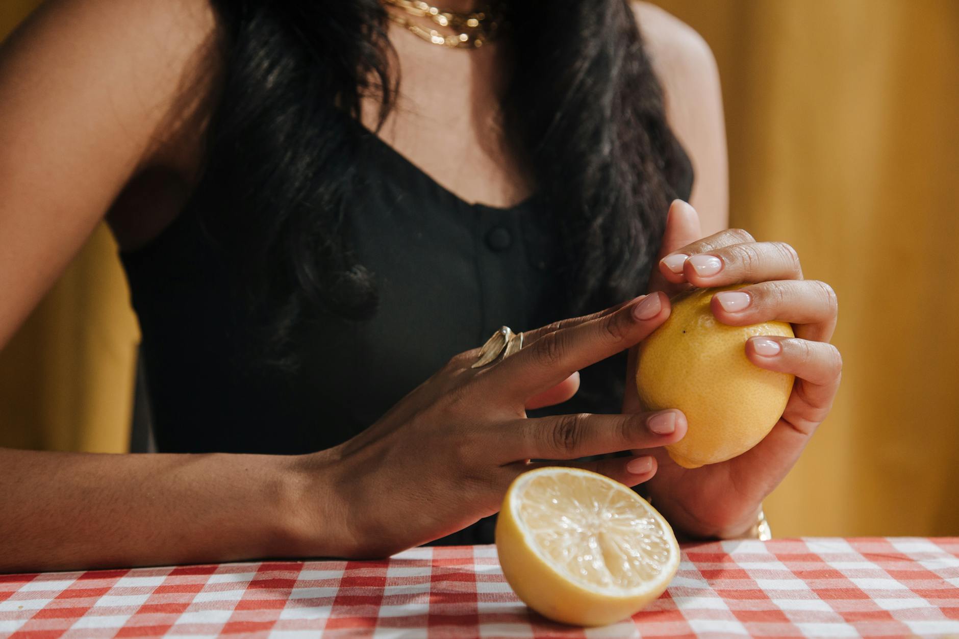 Hand holding an orange vibrator against a minimalistic purple backdrop
