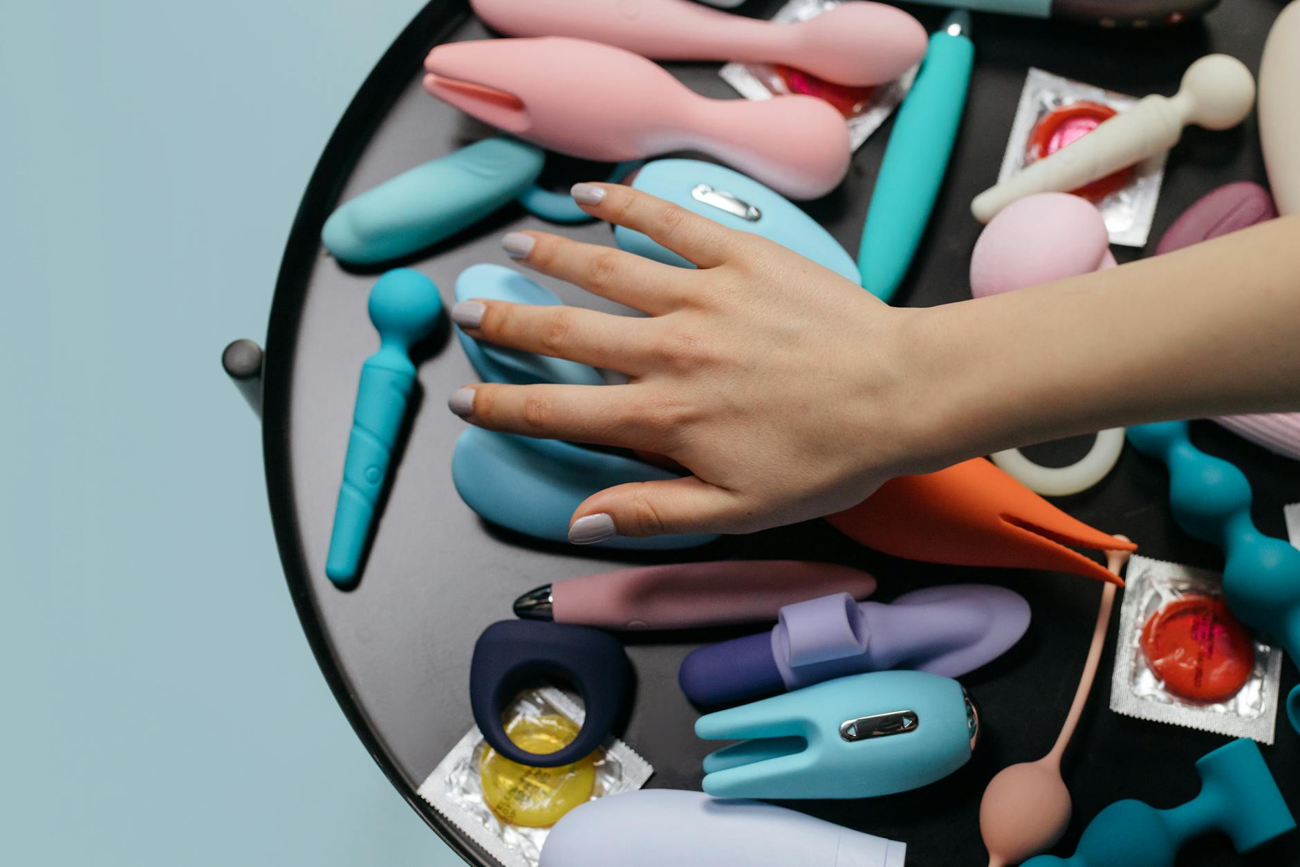 Close-up of hands holding a personal massager against a knitted sweater, representing intimate couple communication