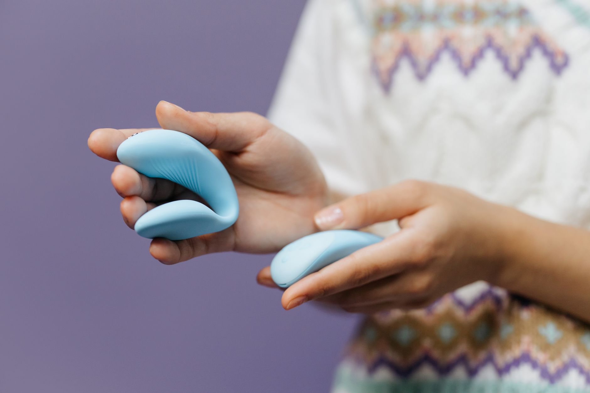 Couple holding a blue clitoral vibrator together, representing shared intimacy and extended pleasure.