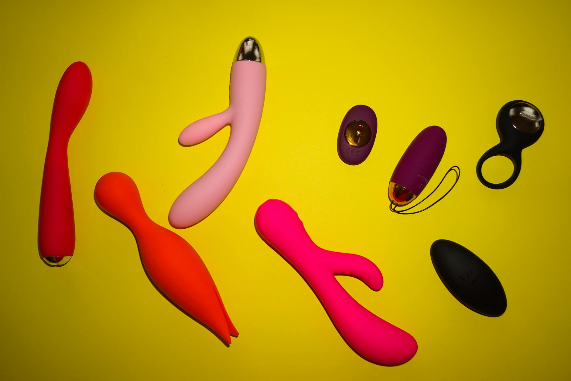 Colorful vibrators displayed on bright yellow background, representing sex toy diversity and openness