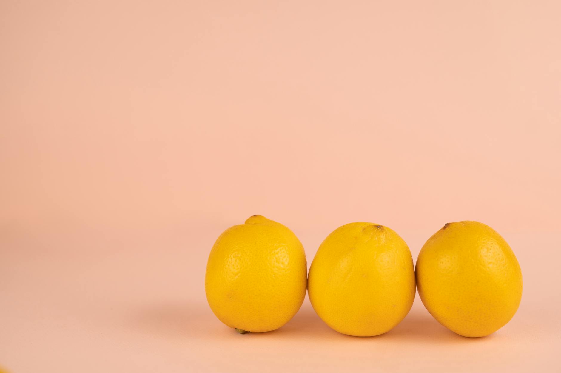 Fresh lemon halves on a pink background catching sunlight, symbolizing sensitivity and gradual opening