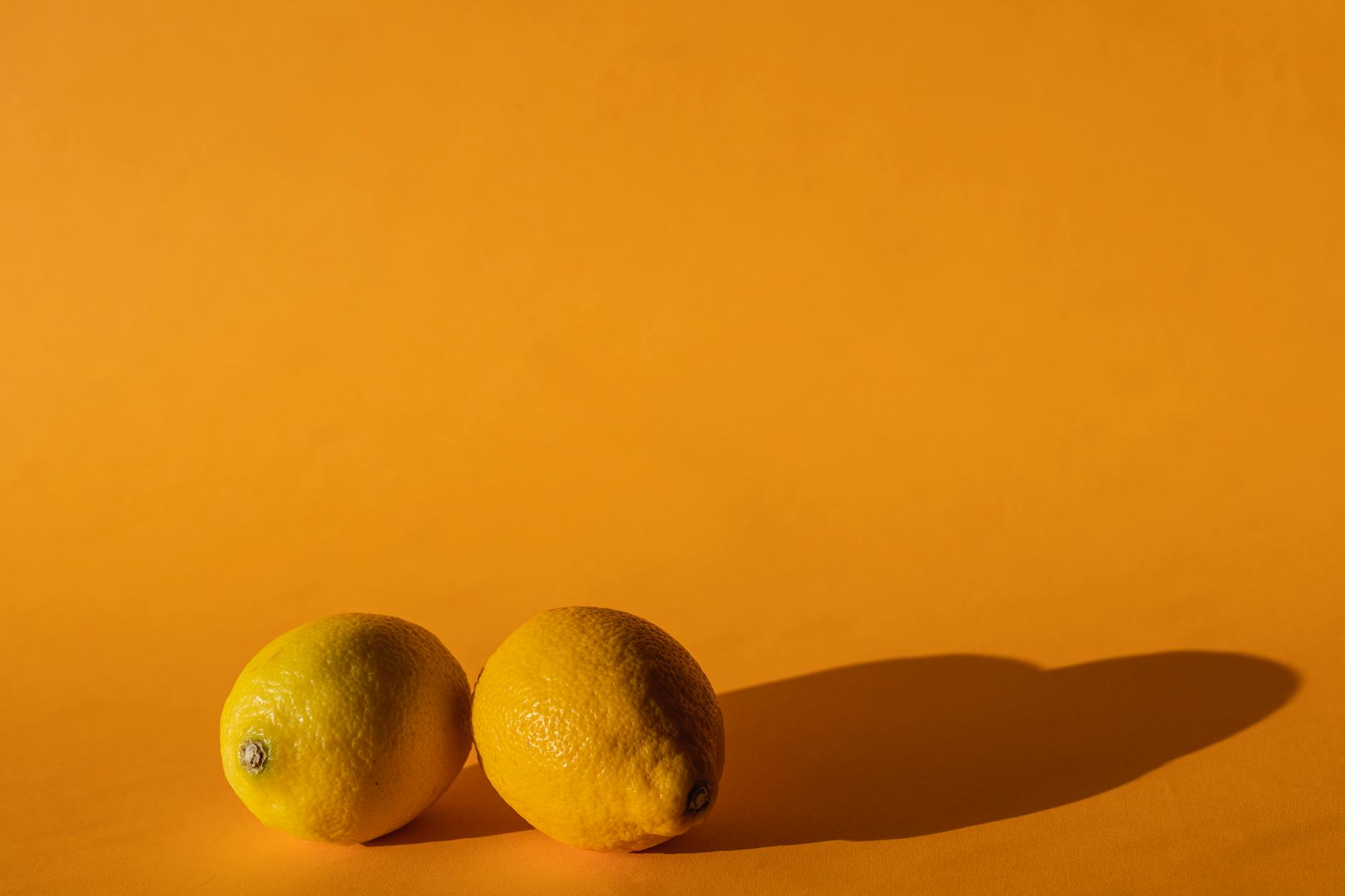 Yellow silicone vibrator surrounded by fresh fruit on a bright background